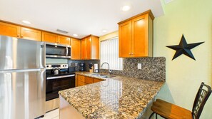 A kitchen with granite countertops, stainless steel appliances, wooden cabinets, and a black star decoration on the wall. - Treasure Island Beachfront-Top Floor End Unit Stunning Sunsets South Beach 601 (Treasure Island)