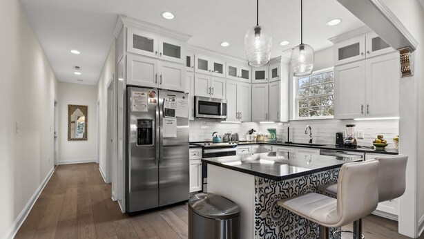 A modern kitchen with white cabinetry, stainless steel appliances, a patterned island, and pendant lighting. - Cottage Glyn - 3 BR Home Steps to the Beach (North Myrtle Beach)