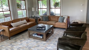 A living room with two leather sofas, a coffee table, and a patterned rug. - Fully Renovated In-Town Family-Friendly Home (Crested Butte)