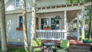 A covered porch with a white railing, a small table, and two chairs. - Fully Renovated In-Town Family-Friendly Home (Crested Butte)