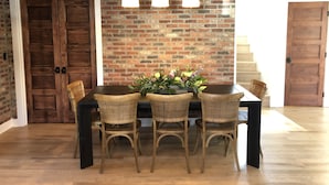 A dining area with a brick wall, wooden doors, and a table with wicker chairs. - Fully Renovated In-Town Family-Friendly Home (Crested Butte)