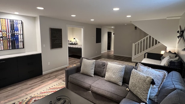 A modern living room with a sectional sofa, a coffee table, and a patterned rug. There is a staircase leading to an upper level. - Fully Renovated In-Town Family-Friendly Home (Crested Butte)
