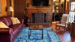 Una sala de estar acogedora con chimenea, un sofá de cuero, una mesa de centro y un televisor.