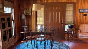 Un comedor con una mesa y sillas de madera, un tapete azul estampado y suelo de ladrillo.