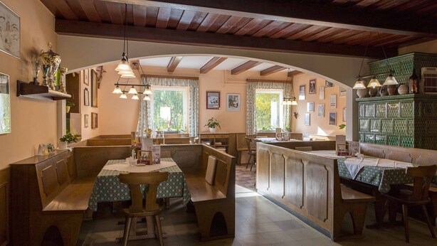 A cozy restaurant with wooden benches and tables, a central island, and a green patterned cabinet.