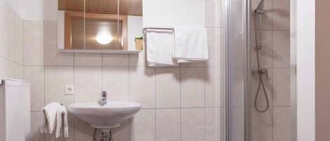 Un baño con lavamanos, espejo y ducha.