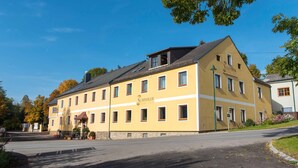 A yellow building with multiple windows and a sign that reads "Schindler Gaststuhf - Pension."