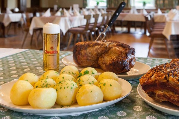 Una mesa de comedor con platos de comida, una botella de cerveza y un tenedor de carne.