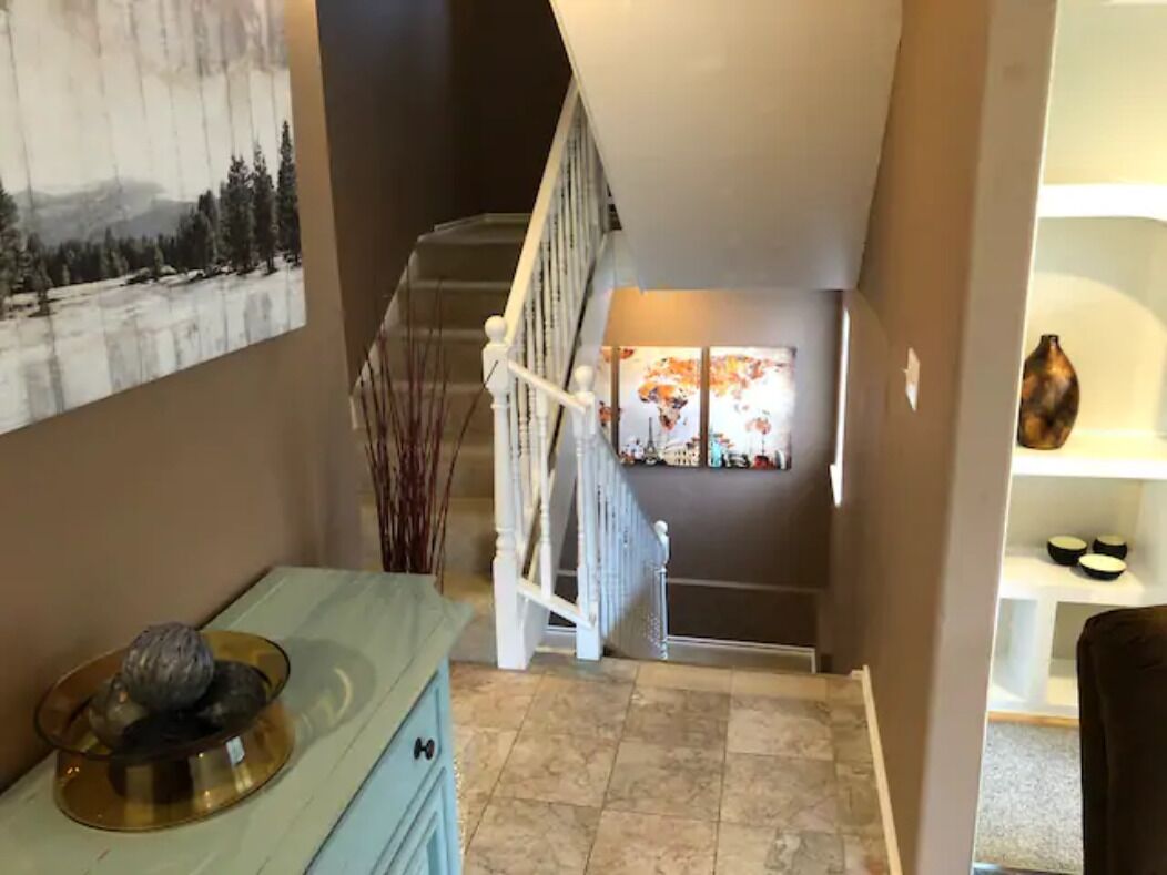 A staircase leading to a second floor with a painting of a snowy landscape above it.