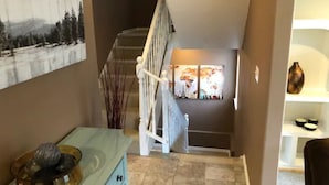 A staircase leading to a second floor with a painting of a snowy landscape above it. - Moden West Seattle House in the Trees (Seattle)