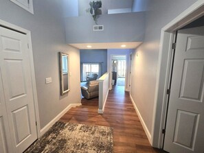 A hallway with wooden flooring, white doors, and a staircase leading to a living area. - Fairway Villa 1501 at Rumbling Bald (Lake Lure)