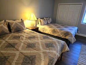 Une chambre avec deux lits, une table de chevet avec une lampe et un placard.