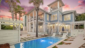 A two-story house with a swimming pool, outdoor seating, and a balcony.