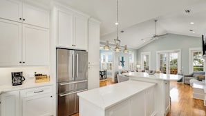 A spacious kitchen with white cabinetry, stainless steel appliances, and a large island.