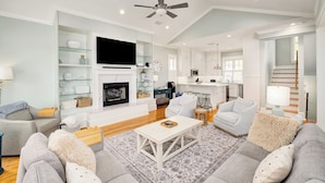 A spacious living room with a fireplace, a television, and a ceiling fan.
