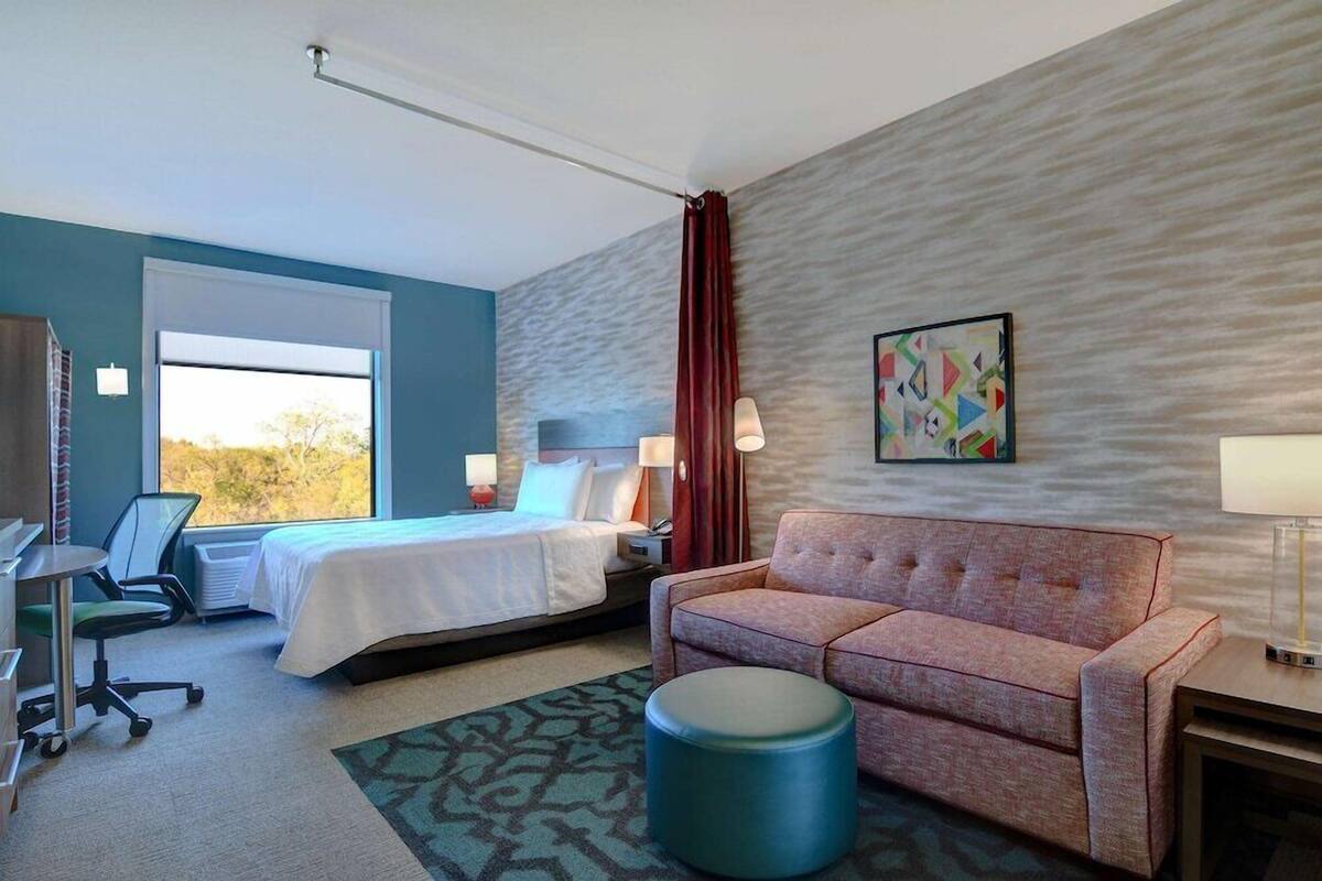 Una habitación de hotel con cama, sofá, escritorio y silla.