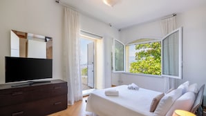 A bedroom with a bed, a TV, a dresser, and a window with curtains. - CASA ANGELICA LUXURY VILLA (Priora)