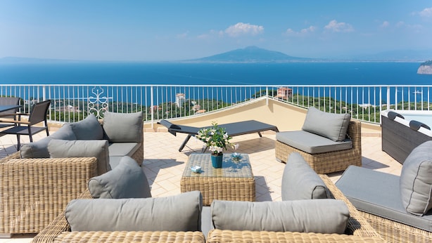A terrace with wicker furniture and a view of the sea and a mountain. - CASA ANGELICA LUXURY VILLA (Priora)