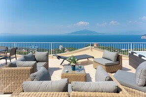 Una terraza con mobiliario de mimbre y vistas al mar y a la montaña.