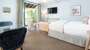 A bedroom with a bed, a chair, a desk, a TV, and a window with curtains. - Palihouse Santa Barbara (Santa Barbara)