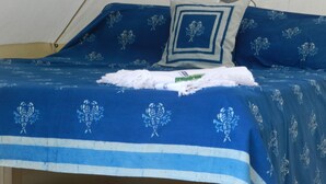 A bed with a blue bedspread featuring a floral pattern, a white pillow, and a blue pillow with a geometric design. - Cosy 5m Bell Tent Glamping in Rural Herefordshire (Hereford)