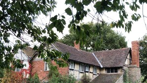 A traditional stone house with a tiled roof, surrounded by a well-maintained lawn and a bench. - Cosy 5m Bell Tent Glamping in Rural Herefordshire (Hereford)