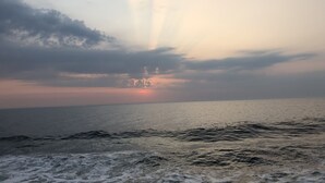 Mar tranquila con rayos de sol filtrándose entre las nubes, creando un ambiente sereno.