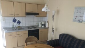 Una cocina compacta con fregadero, estufa y zona de comedor con mesa redonda y sofá.