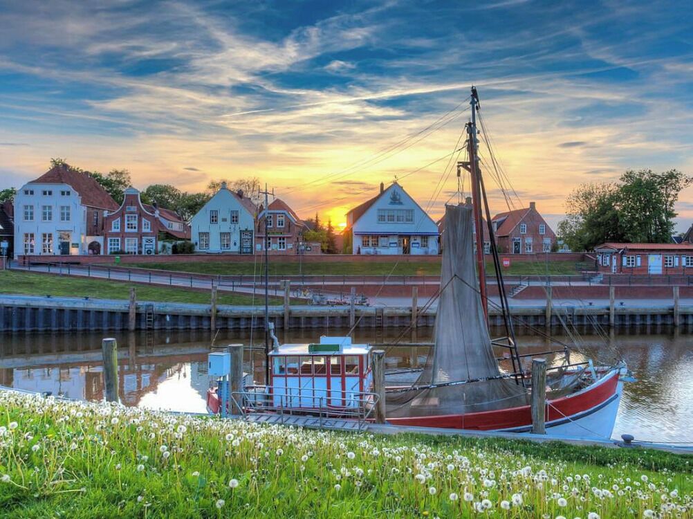 A boat docked near a canal with houses in the background.