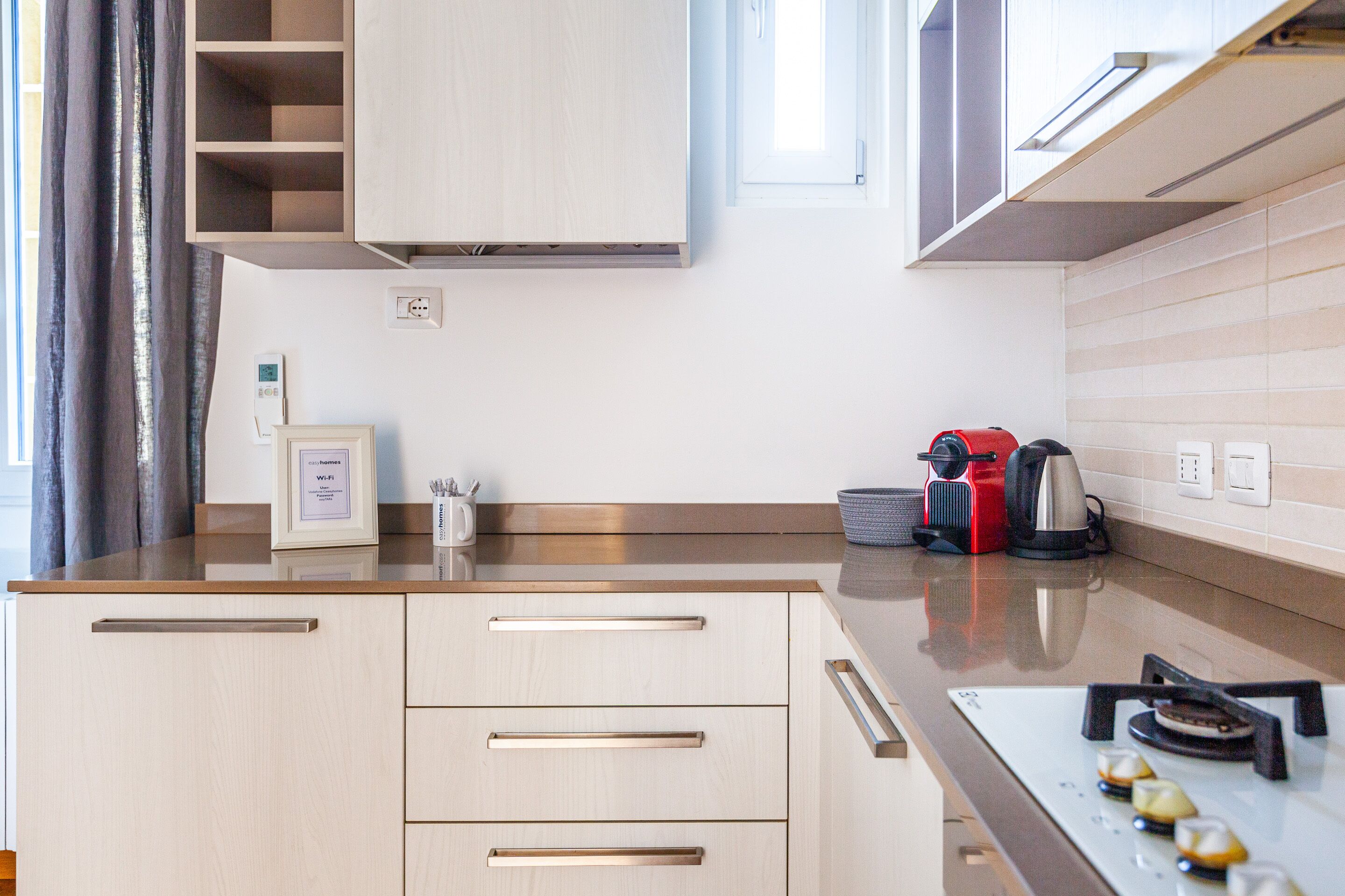 A modern kitchen with light wood cabinetry, a stainless steel range, and a built-in oven.