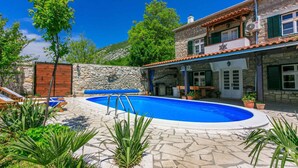 Edificio de piedra con piscina, mobiliario exterior y plantas en macetas.