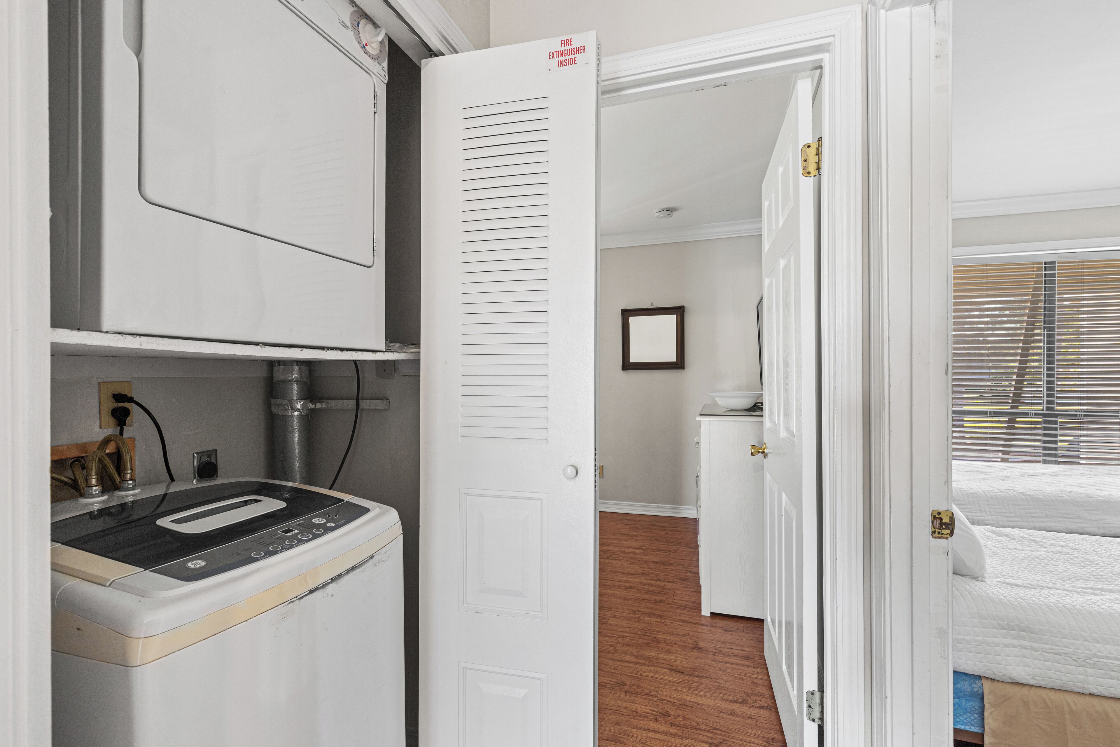 A compact hotel room with a kitchenette, a bed, and a bathroom.