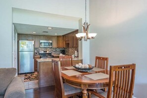 A modern kitchen with granite countertops, a built-in oven, and a dining area with wooden chairs and a table.