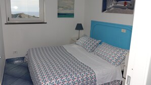Een slaapkamer met een bed, een raam, een airconditioner, een lamp en kunst aan de muren.