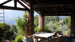 Une terrasse extérieure avec une table et des chaises, une vue sur les montagnes et une structure de pergola en bois.