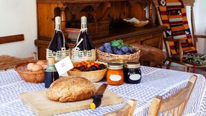 Une table avec du pain, des œufs et des paniers de fruits, ainsi que des bouteilles et des bocaux.