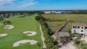 Un parcours de golf avec des bunkers de sable, un sentier pédestre et un pont menant à un bâtiment doté d’un balcon.