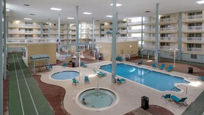 Une piscine intérieure dotée de plusieurs couloirs de nage, de chaises longues et d’un petit bassin pour enfants.