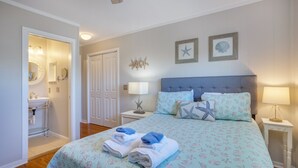 Une chambre à coucher comprenant un lit, une table de chevet, une commode, un miroir et une salle de bain.