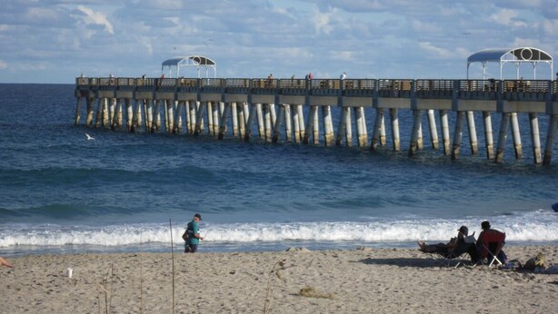 Eine Pier, die sich ins Meer erstreckt, mit Menschen, die darauf laufen und sitzen.