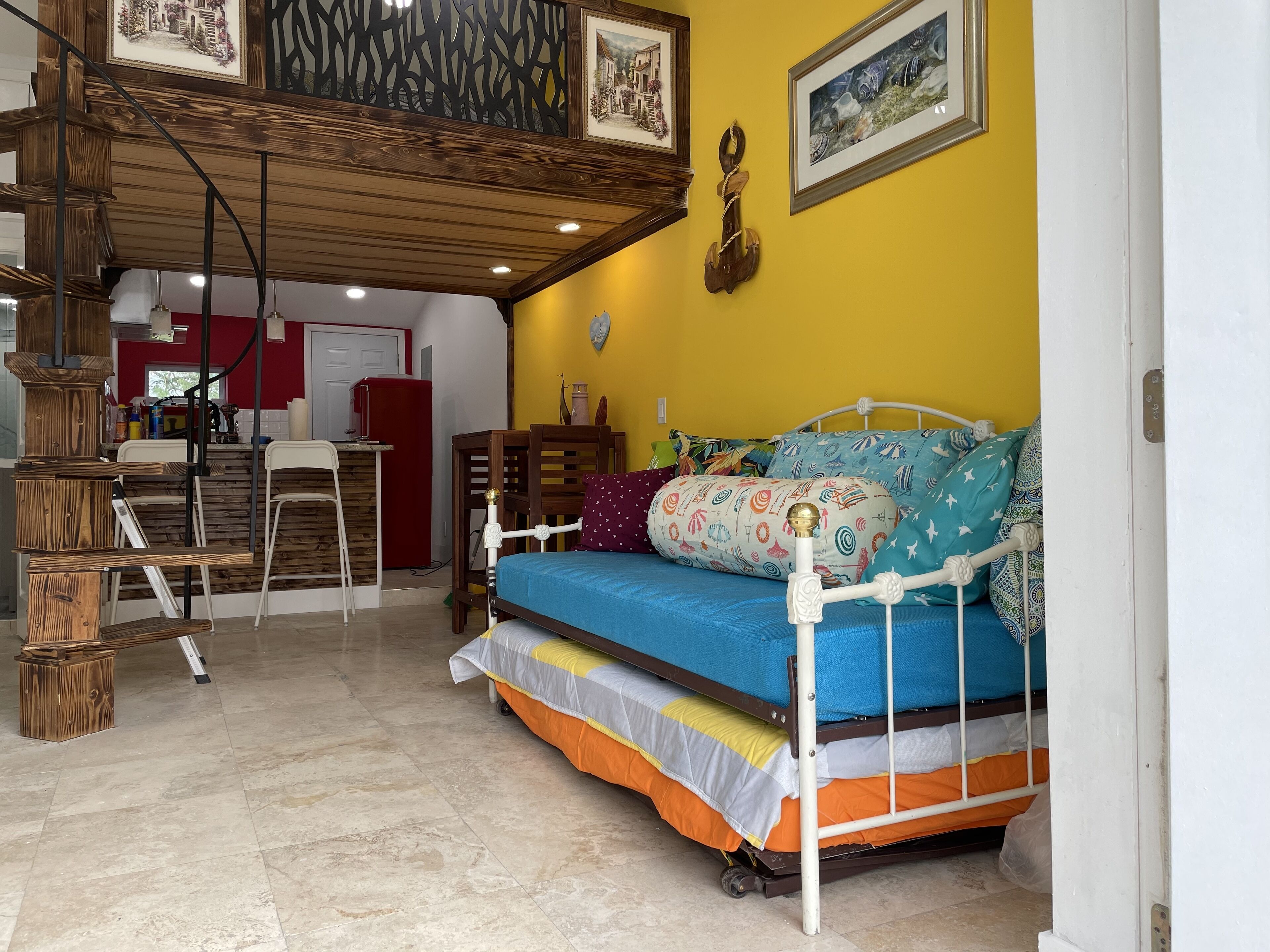 A compact living space with a bed, a small kitchen area, and a staircase leading to an upper level.