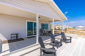 A covered deck with Adirondack chairs, a table, and a sliding glass door leading to a balcony. - Blue Tortoise - Awesome Oceanfront Deck!  Dog Friendly! (North Topsail Beach)