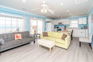 A compact living space with a sofa, a small table, and a kitchenette. - Blue Tortoise - Awesome Oceanfront Deck!  Dog Friendly! (North Topsail Beach)