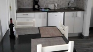 A compact kitchen with white cabinets, a microwave, a coffee maker, and a wine bottle on the counter.