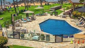 Un espace piscine avec des chaises longues, une petite piscine et une vue sur la plage.