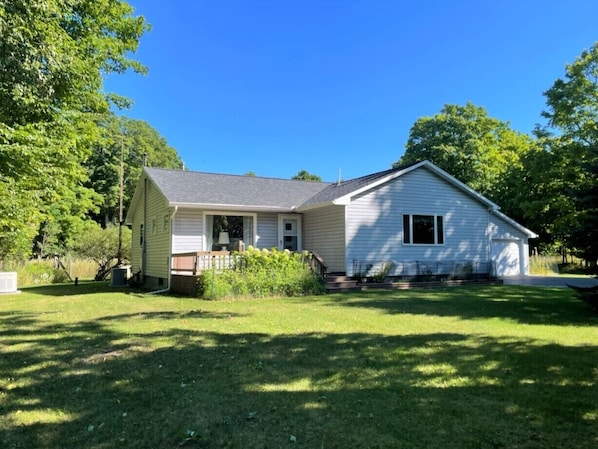 A single-story house with a front porch, a small garden, and a clear blue sky.