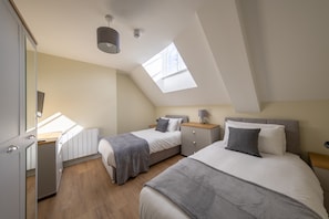 Une chambre avec deux lits, une lucarne, un bureau et une armoire.