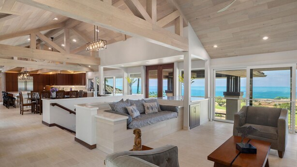 A spacious living area with a large island, a dining area, and a view of the ocean.