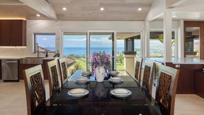 A dining area with a large table, chairs, and a vase of flowers.