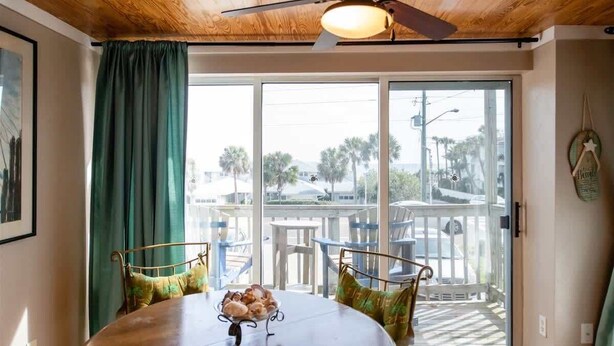 A dining area with a wooden table, metal chairs, and a ceiling fan. - Wanna Sea #201 - Newly Constructed Balcony! (Fernandina Beach)